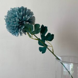 Flor de pompon azul artificial en un jarrón de cristal transparente